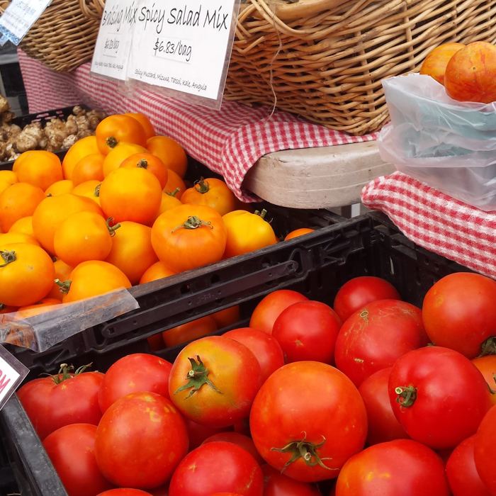 Market stall piled with tomatoes and squash