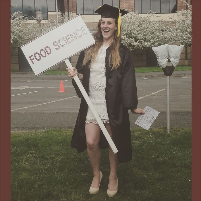 Julia in cap and gown holding a Food Science sign