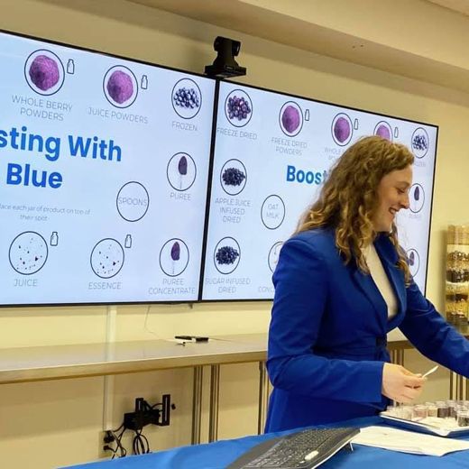 Julia in a blue blazer presenting blueberry ingredients for the U.S. Highbush Blueberry Council